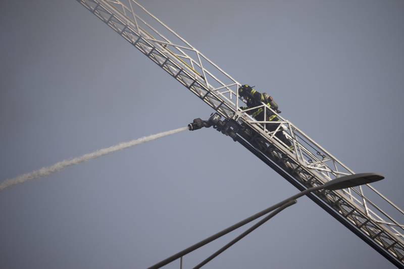 A Joliet firefighter guiding a water hose on a ladder as part an effort to fight a fire at an apartment building on Tuesday, June 10, 2025, near Essington Road in Joliet.