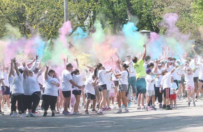 Hundreds of runners line up at the starting line while releasing color powder in the air for the Color Fun Run on Sunday, April 26, 2026 at Lake Mendota.