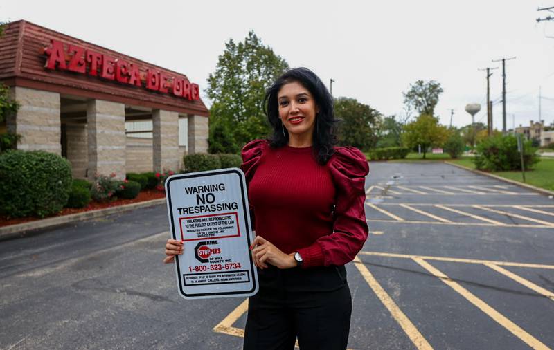 Ivette Nunez, manager of the Azteca de Oro banquet hall, holds a no-trespassing sign in the parking lot of the banquet facility.