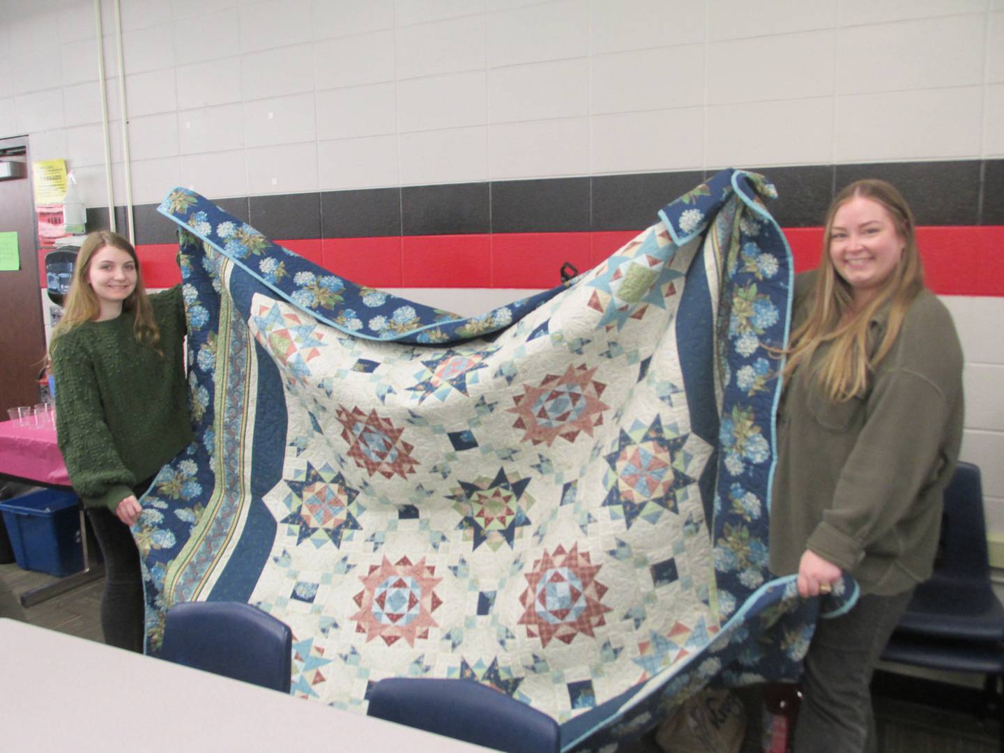 Woodland senior Shay Wilcoxen (left) holds up the quilt won in a raffle by Melanie North (right) on Tuesday, April 25, 2023, after Wilcoxen was named the first Beckie Chismarick Community Service Award winner.