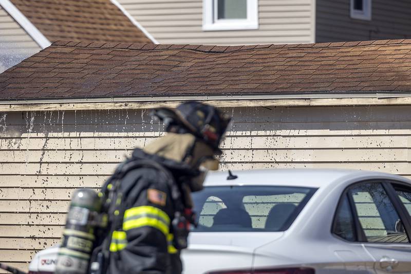 Water pours out of the eave of a backyard shed Friday, March 14, 2025, while firefighters douse the flames in Dixon.