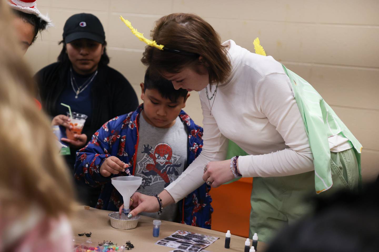 Olivia Kuncis, right, a student at Lewis University helps Luis Roman, 8, from Joliet make a potion at the STEAM Spooktacular hosted by the After the Peanut Foundation on Wednesday at Lewis University.