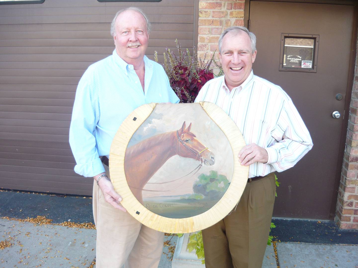 Cary businessman Bob Harper and Mayor Tom Kierna hold a painting of Reigh Count by Frank Griggs. Reigh Count, owned by John and Fannie Hertz, was a thoroughbred horse, the Kentucky Derby winner in 1928, and was housed on the Hertz' 940-acre estate in what became the village of Trout Valley.