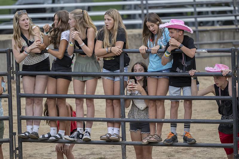 Morrison junior high friends climb the fence for a better view of a kid’s race Wednesday, August 14, 2024, at the Whiteside County Fair in Morrison.
