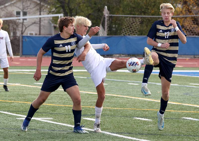 Prairie Ridge's Logan Braun kicks the ball between Lemont's Mitchell Sowa (left) and Andrew Guzy Saturday, Nov. 9, 2024, during their Class 2A state third place game at Hoffman Estates High School.
