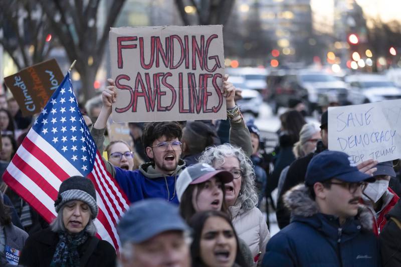 People protest against a funding freeze of federal grants and loans following a push from President Donald Trump to pause federal funding near to the White House in Washington, Tuesday, Jan. 28, 2025. (AP Photo/Ben Curtis)
