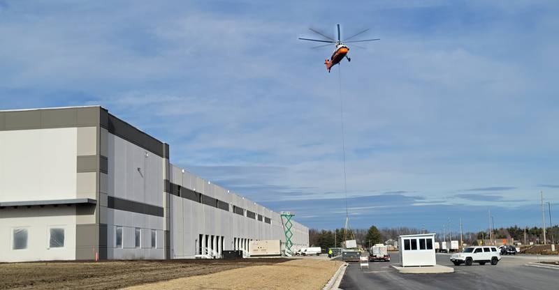 A 1962 Sikorsky helicopter lifts one of 10 heating and air conditioning units onto the roof of the new Ollie’s Bargain Outlet warehouse near the intersection of Interstate 80 and Illinois Route 26 in Princeton on Friday morning. The helicopter, according to an employee of Midwest Helicopters in Willowbrook, has a maximum lifting capacity of 5,000 pounds, so it managed to handle with ease the units that ranged in weight from 1,000 to 2,500 pounds in less than half an hour.