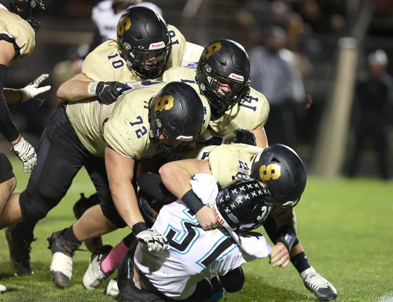A host of Sycamore defenders take down Woodstock North's Kaden Combs in the backfield during their game Friday Oct. 7, 2022, at Sycamore High School.