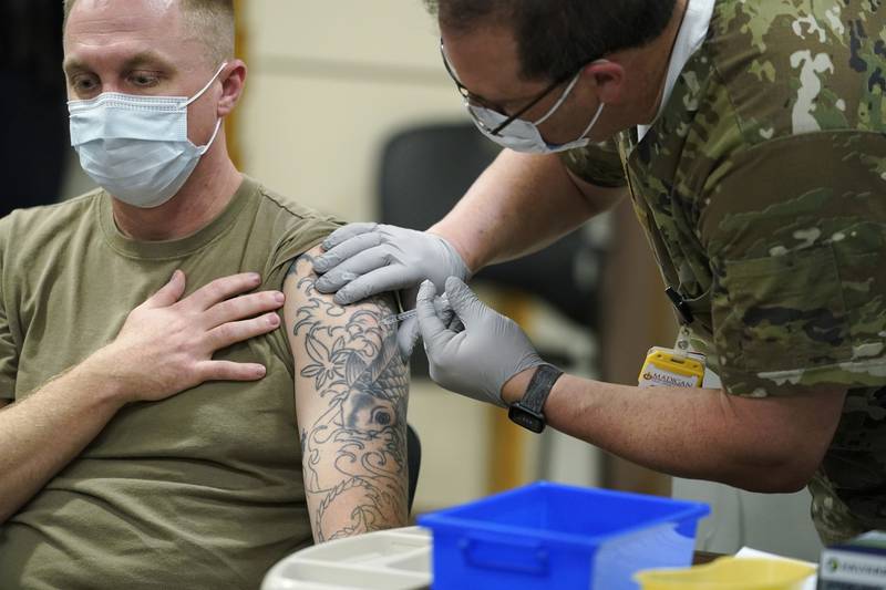 FILE - Staff Sgt. Travis Snyder, left, receives the first dose of the Pfizer COVID-19 vaccine given at Madigan Army Medical Center at Joint Base Lewis-McChord in Washington state, Dec. 16, 2020, south of Seattle. The Army says 98% of its active duty force had gotten at least one dose of the mandatory coronavirus vaccine as of this week’s deadline for the shots.