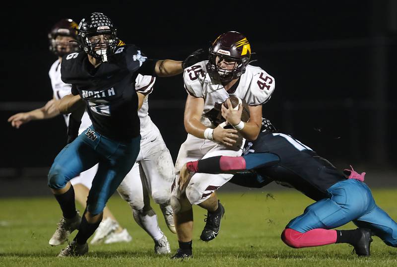 Richmond-Burton's Riley Shea (center) tries to break the tackle of Woodstock North's Braelan Creighton (right) as his teammate, Michael Pintor, (left) closes in during a Kishwaukee River Conference football game on Friday, Oct. 10, 2025, at Woodstock North High School.