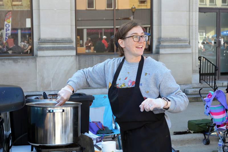 Amanda Shuman, of Polo, stirs a traditional chili while she looks over her shoulder at an attendee of the Polo Chili Cook-Off and Block Party on Saturday, Sept. 28, 2024, in downtown Polo.