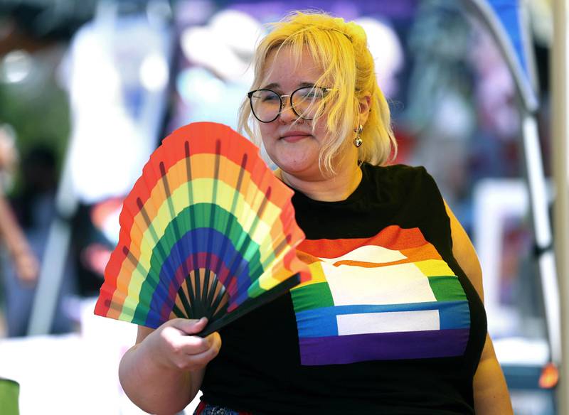 Emma May, from DeKalb, uses a fan in the shade of one of the tents to keep cool on a hot and humid Saturday, June 21, 2025, during the DeKalb Pride Fest in front of the Egyptian Theatre in DeKalb.