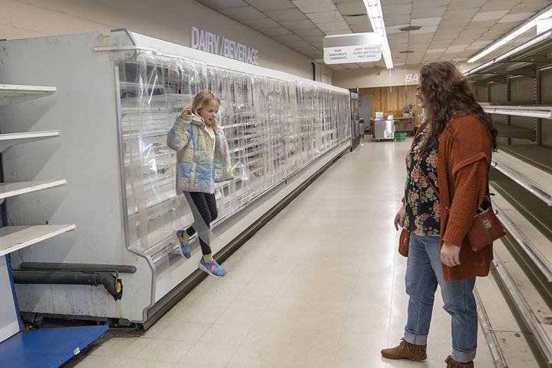 Georgia Blayney, 8, hops down after exploring the empty dairy case with Katharine Leslie Saturday, April 4, 2026, at Oliver’s Corner Market.