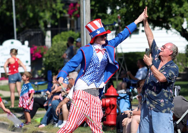 Ash Jorenby-Behling receives a high five as he marches with the crew from PetVet during the Huntley Independence Day Parade along Main Street in Huntley on Friday, July 4, 2025.