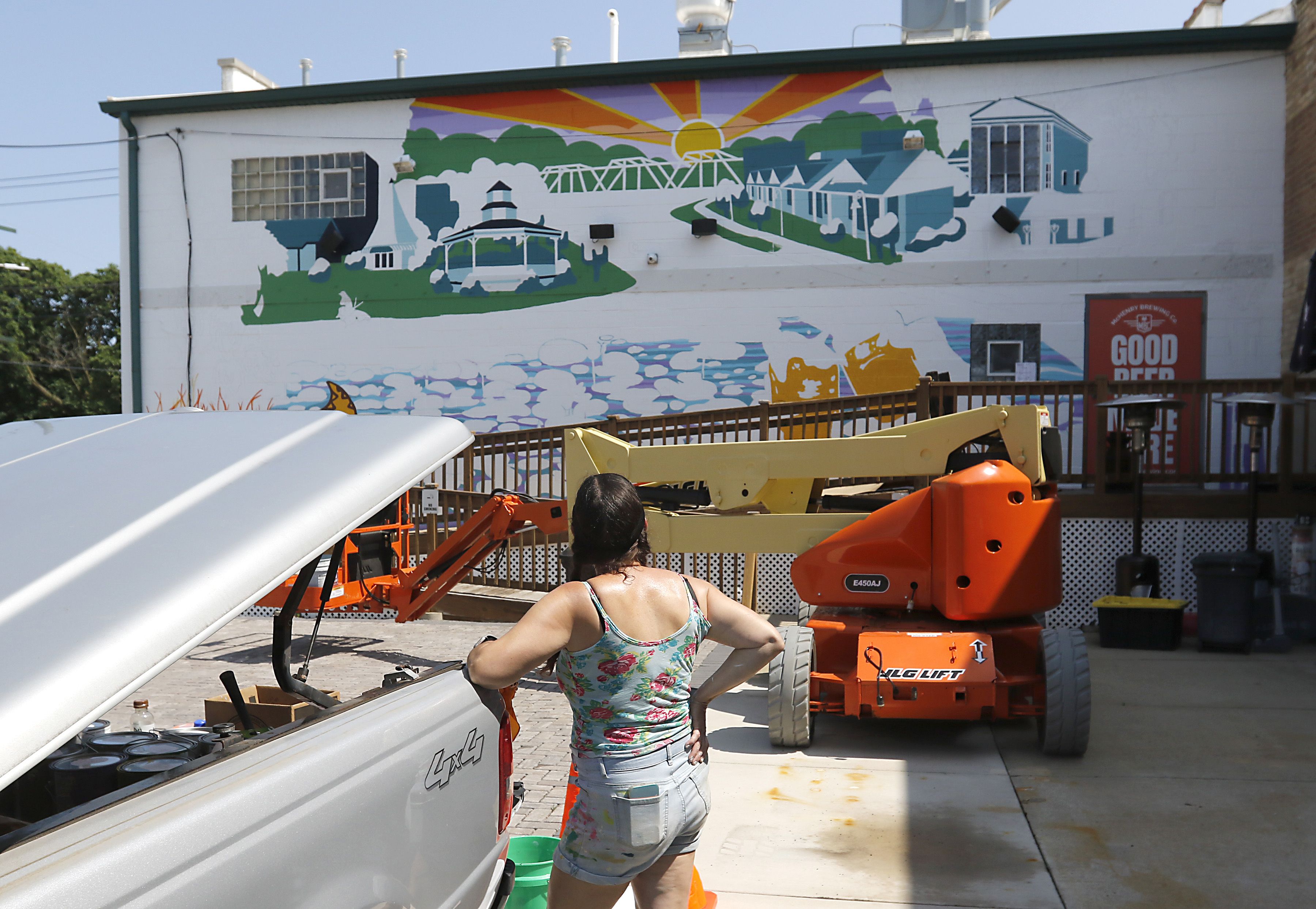 Jenny Mathews surveys the progress as she paints a mural on Thursday, June 19, 2025, on the side of the McHenry Brewing Co., in McHenry. This is one of two new McHenry murals in McHenry. 