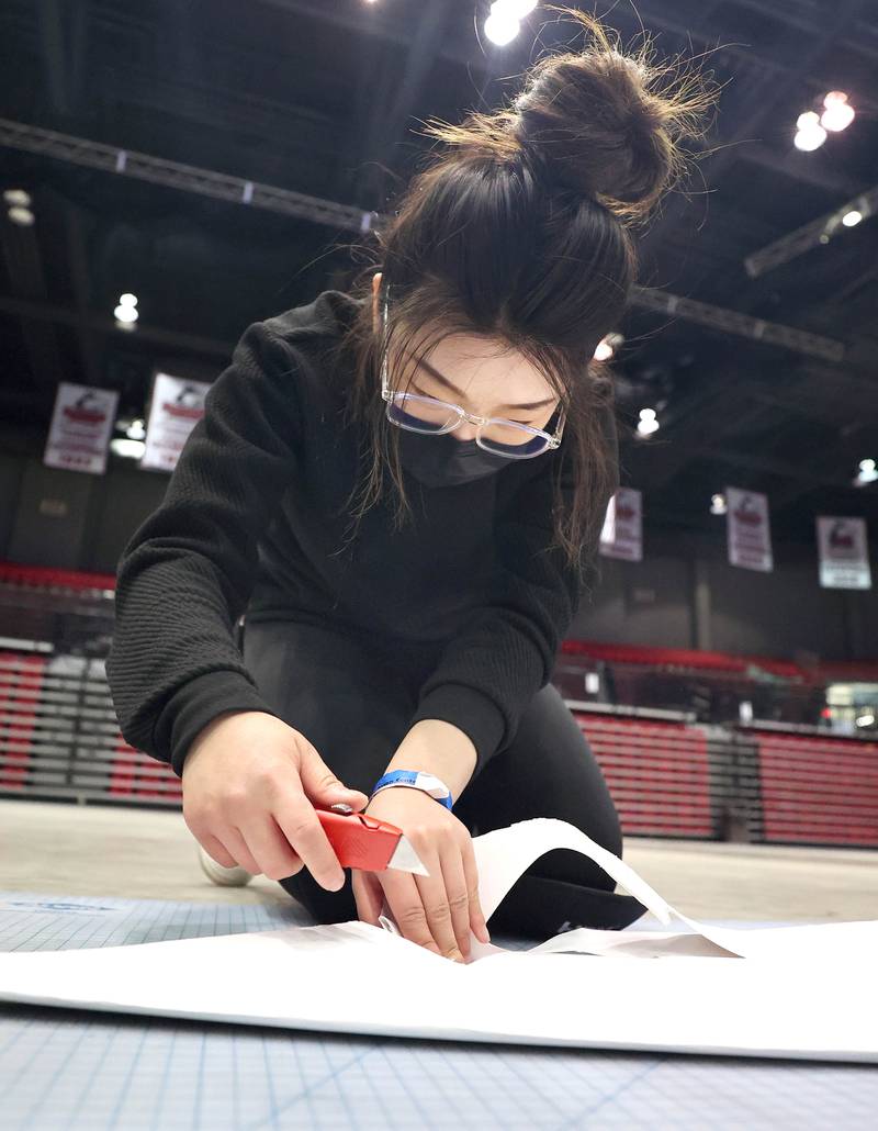 Northern Illinois University senior Qiming Ruan makes the first cuts on the giant paper snowflake she is making with her fellow photography students Tuesday, March 29, 2022, in the Convocation Center at NIU in DeKalb. The students are attempting to break the world record for the largest paper snowflake.