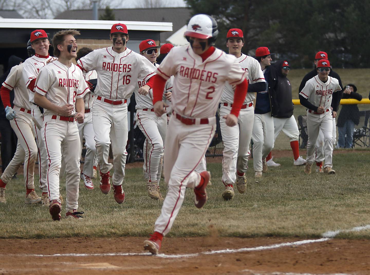 Huntley players run onto the filed as Huntley's Kyle Ziebell runs to home after Joey Lengle walked in the ninth inning scored a run to win a nonconference baseball game against Fremd on Tuesday, March 24 2026, at Huntley High School.