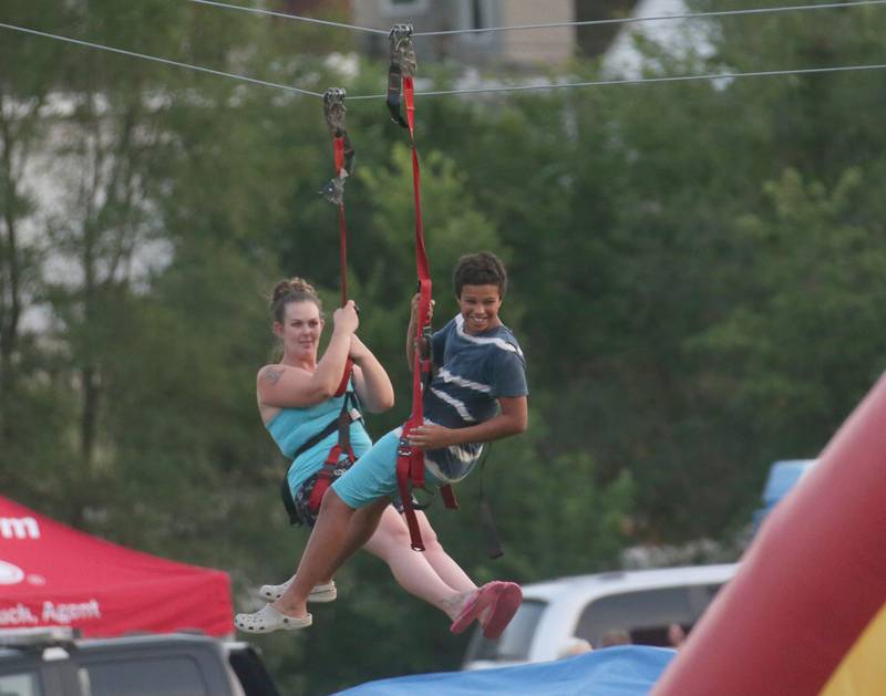 Cindy Waltz and her son Kamarlie of Peru, take a zipline ride during the Taste of the Illinois Valley festival on Saturday, Aug. 3, 2024 at Centennial Park in Peru.