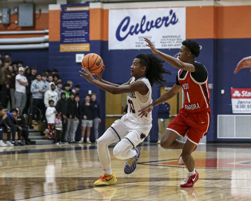 Oswego's MJ Johnson (10) passes while driving down the lane during their basketball game between West Aurora at Oswego Monday, Nov 24, 2025 in Oswego.