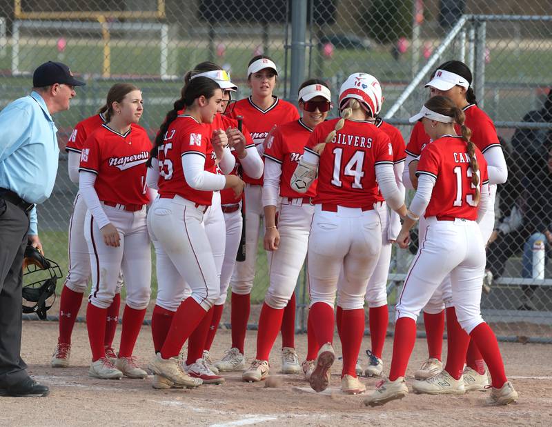 Naperville Central's Riley Silvers is welcomed home by her teammates after homering Wednesday, April 16, 2025, during their game at DeKalb High School.