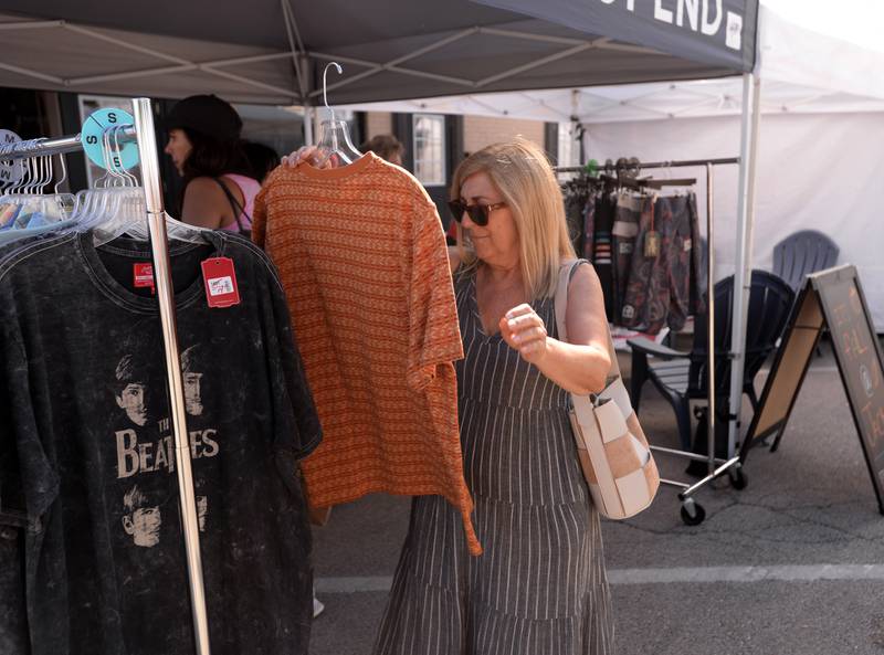 Gina Francia of Westchester looks over one of the shirts outsideWest End during the West End Arts Festival in LaGrange Saturday, Sept. 21, 2024.