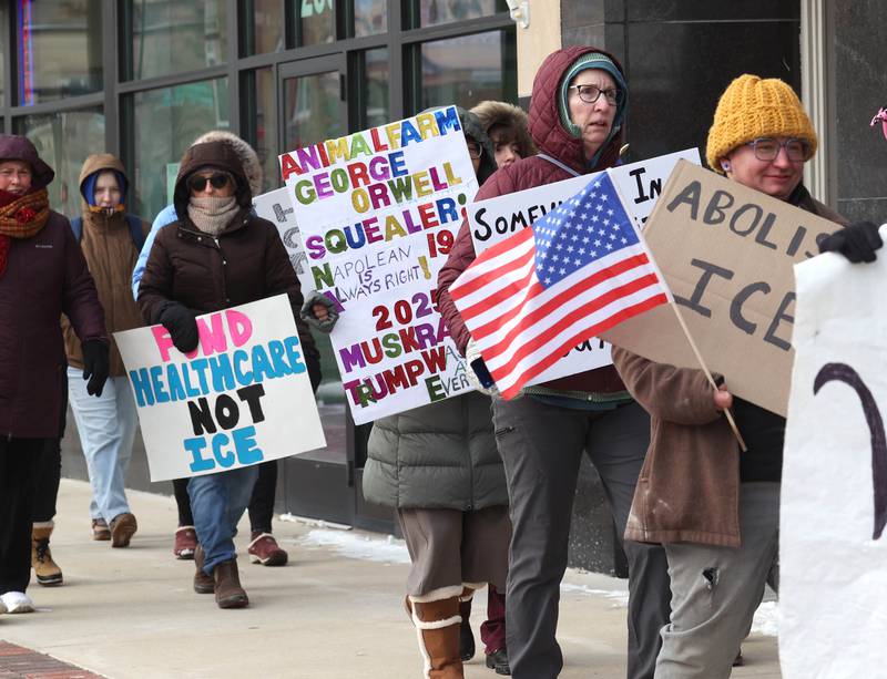 Protesters chant and carry signs as they march west down the sidewalk on Lincoln Highway in DeKalb Tuesday, Jan. 20, 2026, as part of a larger national Free America Walkout. The group is protesting what they perceive as an escalating fascist threat under President Donald Trump and his administration.