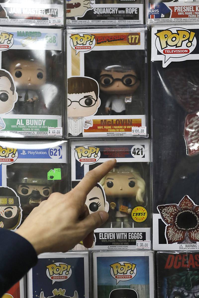 Andrew Rios, the owner of Andy’s World, points out a Funkos Pop for sale on Wednesday, Feb. 5, 2025, inside his store in the Woodstock Square Mall. The store sells Funkos, charms for  CR0CS, metal pins, and posters.