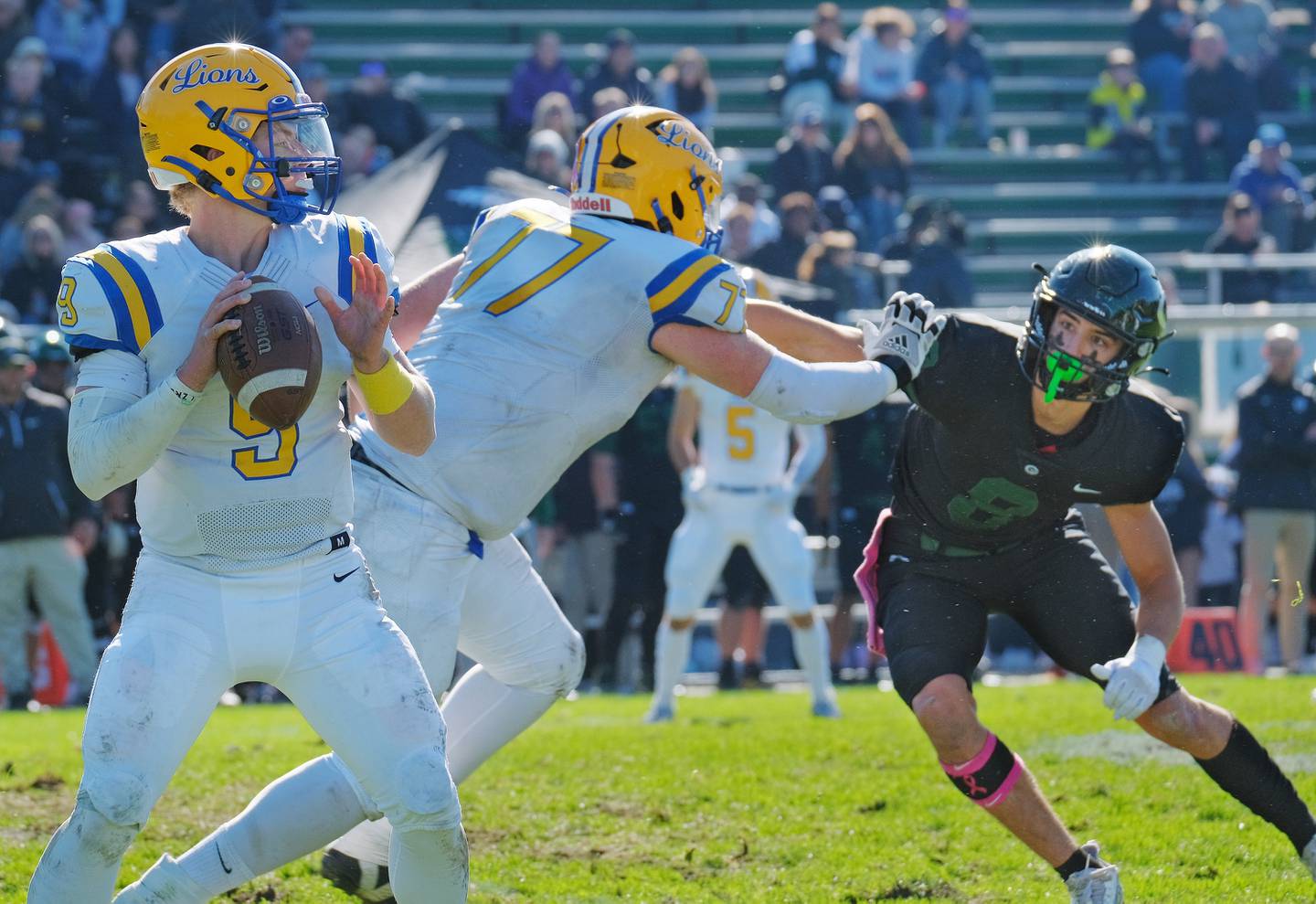 Lyons Township quarterback Ryan Jackson (9) looks for an open receiver while Aidan Hallett (77) tries to hold off Glenbard West's Filip Maciorowski (8) during a game on Oct. 15, 2022 at Glenbard West High School in Glen Ellyn.