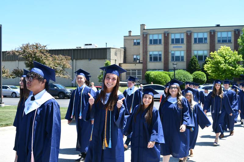 Lily Berner (giving thumbs up) processes into Alexine Chapel followed by Natalia Canino and Lisani Calderone. In the background are Shuyao (Sky) Lu and Alex Marino during Nazareth Academy’s commencement ceremony in La Grange Park on Sunday, May 21, 2023.