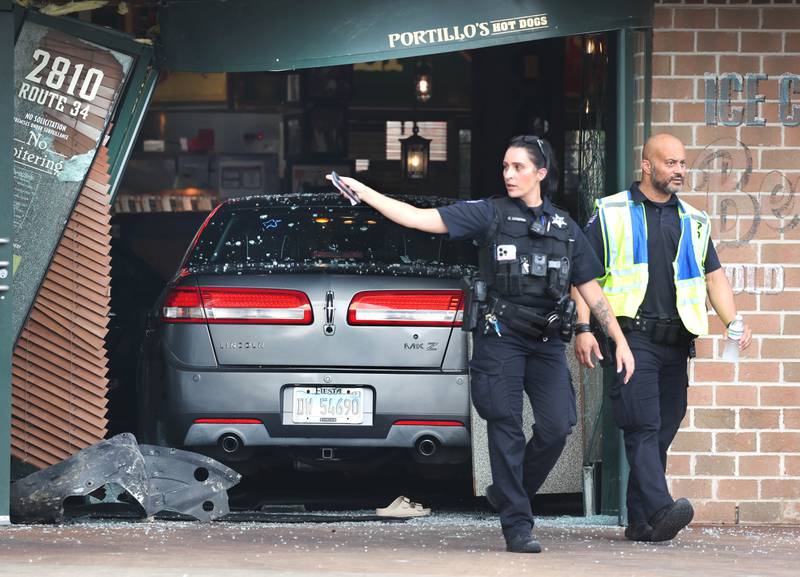 Oswego Police officers exit the Portillo’s Wednesday, July 30, 2025, where a car crashed through the front entrance of the business at 2810 U.S. Route 34 in Oswego injuring 12.