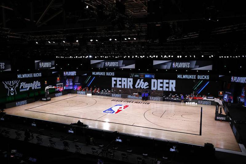 Referees huddle on an empty court at game time of a scheduled game between the Milwaukee Bucks and the Orlando Magic for Game 5 of an NBA basketball first-round playoff series, Wednesday, Aug. 26, 2020, in Lake Buena Vista, Fla. (Kevin C. Cox/Pool Photo via AP)