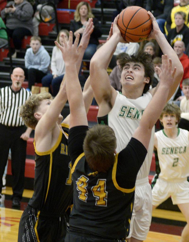 Seneca’s Kysen Klinker gets a shot away over the block attempts of Riverdale’s Brody Clark and Dawson Peterson during the 1st period Friday at Regional Championship at Hall.