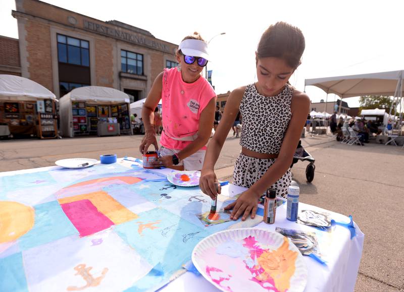 Erika Vazzana of The End Design in Riverside helps children including Vera Singh of Hinsdale create a community art piece during the West End Arts Festival in LaGrange Saturday, Sept. 21, 2024.