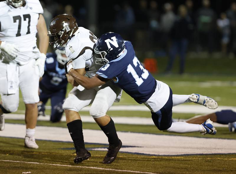 Joliet Catholic's Nate Magrini (28) is wrapped up by Nazareth's Yandiel Colon (13) during the varsity football game between Joliet Catholic and Nazareth academies on Friday, Sep. 27, 2024 in La Grange Park.