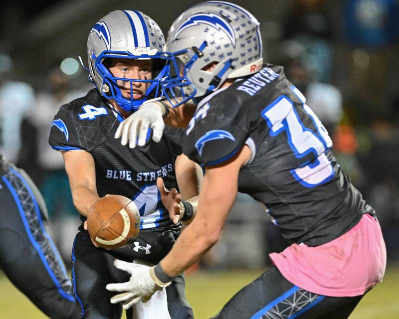 Woodstock's Caden Thompson hnads the ball off to teammate Stewart Reuter during their game against Kishwaukee River Conference and crosstown rival Woodstock North on Friday, Oct. 25, 2024 at Woodstock H.S.