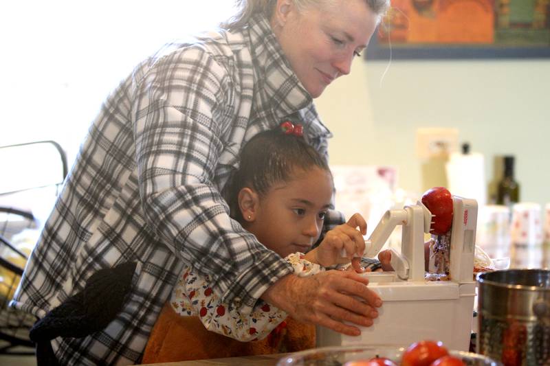 Leslie Meredith, owner of the Farmhouse School in Campton Hills, helps 8-year-old Gabby Del Toro as she spiralizes apples during a Fun Friday with The Learning Door at the Farmhouse School.