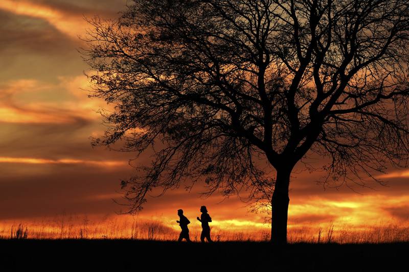 FILE - People are silhouetted against the sky at sunset as they run in a park, Nov. 12, 2024, in Shawnee, Kan. (AP Photo/Charlie Riedel, File)