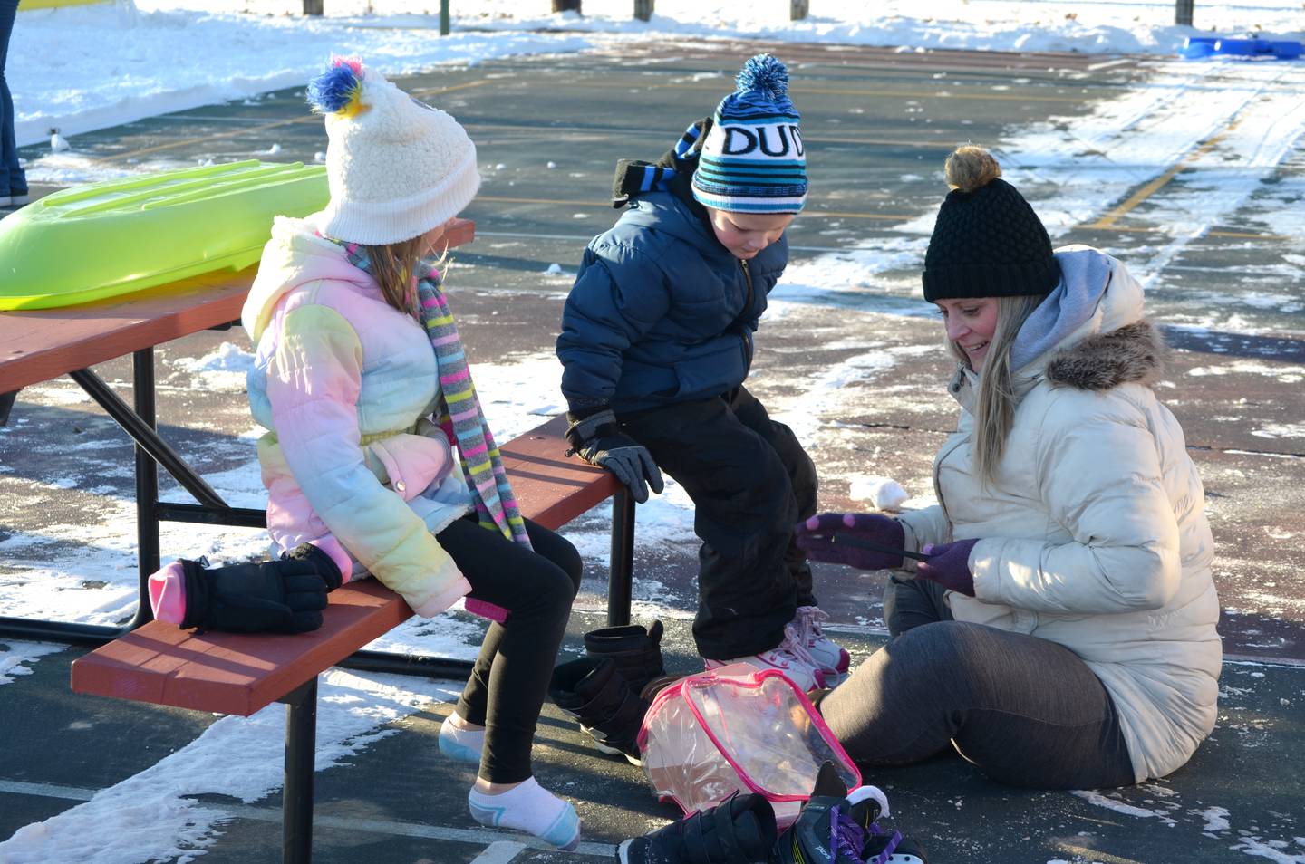 Candi Kuehl of Morrison laces up the ice skates of her children Calvin, 5, and Calista, 7, at Morrison Winter Park on Tuesday, Dec. 27. The family lives near the park and walked over for the grand opening, saying it was their first time for ice skating.