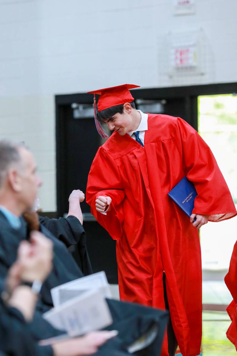 Mason Spitson fist bumps a faculty member after receiving his diploma Friday, May 27, 2022, at Marian Central Catholic High School.