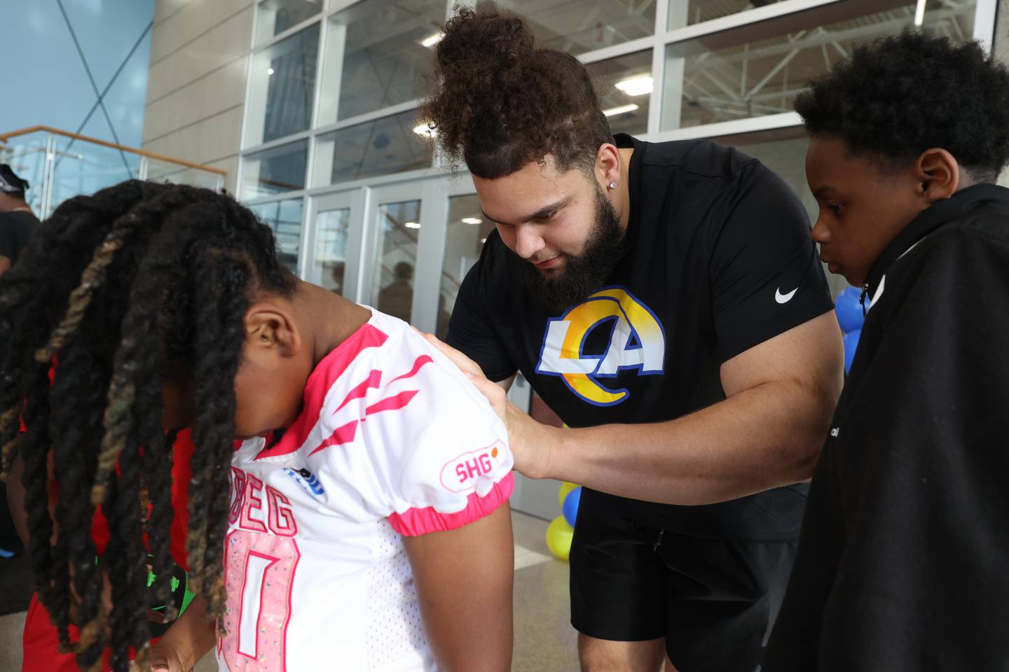 Keagen Trost, a 2019 Kankakee High School grad, signs the jersey of Kyere Smith, 8, of Kankakee, during a celebration held for him at the school on May 4, 2026, following him being drafted into the NFL to the Los Angeles Rams.