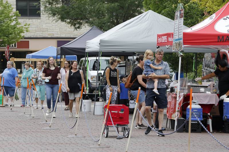 Families wander around the historic Woodstock Square looking at the various products for sale during the Woodstock farmers market on Tuesday, July 13, 2021, in Woodstock.