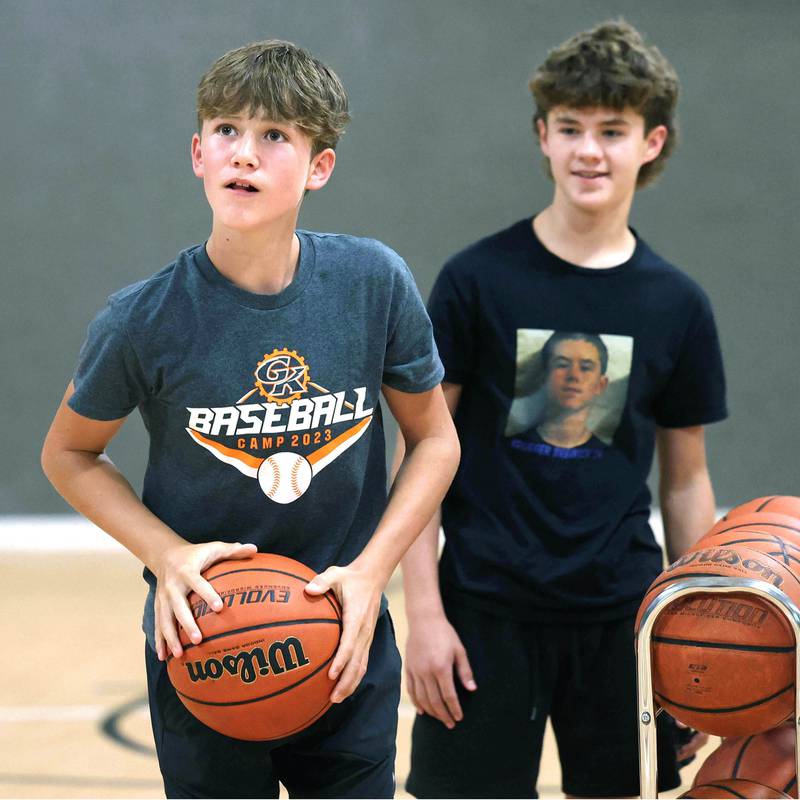 Caleb Krueger, (left) 13, and his brother Cole, 15, practice their three point shots Wednesday, Aug. 28, 2024, at their house in Genoa as they prepare for an attempt to break the world record for three pointers in a minute by a duo. The brothers already own a Guinness Book World Record for the most basketball passes in a minute for a pair under 16.