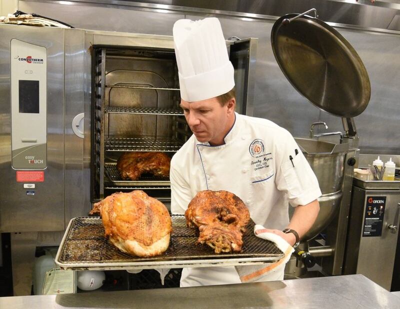 College of DuPage professor Chef Timothy Meyers pulls a pair of finished turkey breasts out of the oven on Monday. He and his culinary students are preparing Thanksgiving meals that will be served to cadets from Great Lakes Naval Station at Villa Park VFW Post 2801. (Rick West | Staff Photographer)