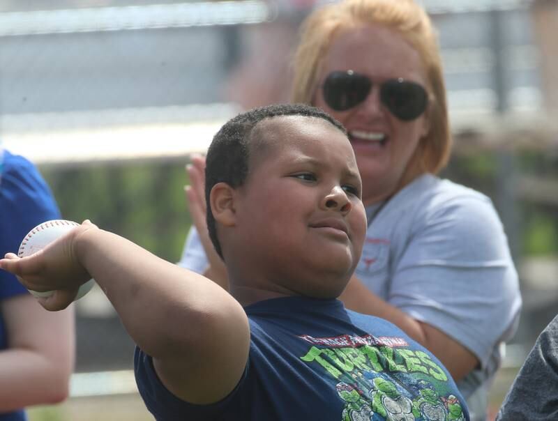 Lighted Way student Grayson throws shot put as instructor Allison Nichols cheers him on during the Lighted Way and Trinity Catholic Academy PALS Spring Track Meet on Monday, May 13, 2024 at the L-P Athletic Complex in La Salle. LighTed way students participated in running, throwing, wheelchair slalom and much more.