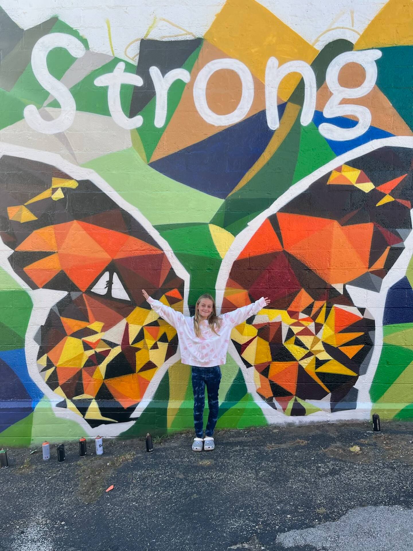 Adi Santos shows how the butterfly wings on the "McHenry Strong" mural will appear in photographs on Saturday, Oct. 22, 2022.