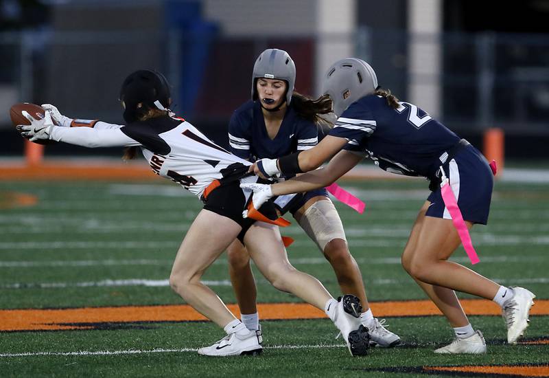 McHenry's Morgan Frederick (left)  tries to gan extra yards as she is stopped by Cary-Grove's Kennedy Manning (center) and  Aria Stanton (right) during the IHSA McHenry Regional girls flag football championship game on Wednesday, Oct. 8, 2025, at McCracken Field in McHenry.