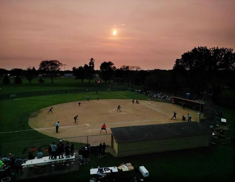 Thursday's sunset over the MSL championship softball game in Buffalo Grove on Thursday. Scientists say the unusual redness of the evening sun will likely continue for months until wildfires raging in Canada burn themselves out. John Starks | Staff Photographer