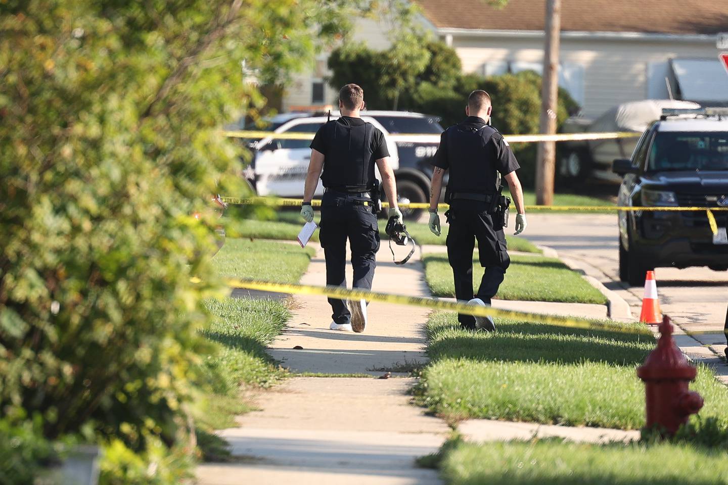 A police photographer heads back to a home on the 500 block of Concord Avenue where police found the bodies of two adults and two children with gunshot wounds on Monday, Sept. 18, in Romeoville.