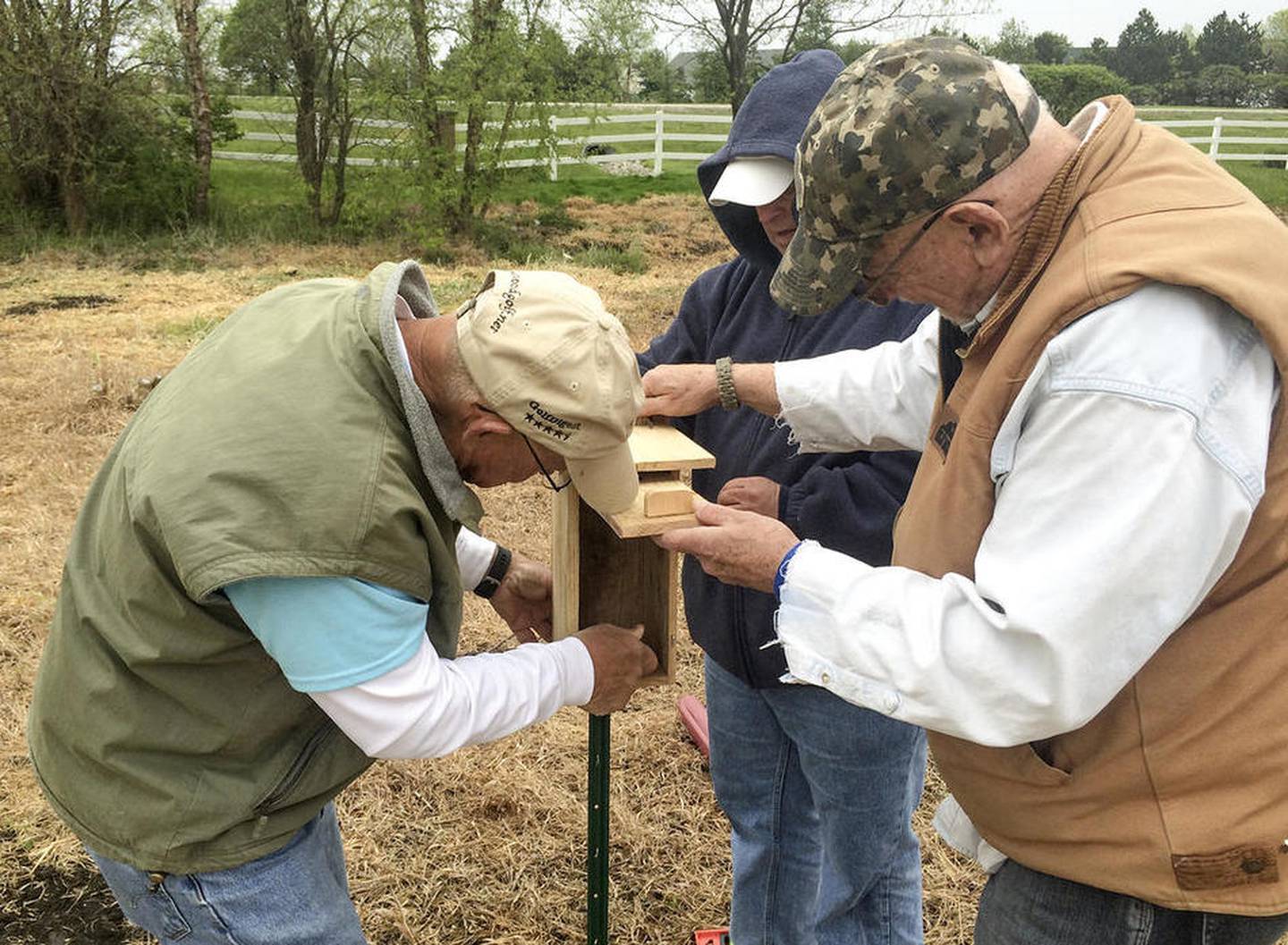 Don Johnson (left), Harry Blackburn (center) and Bob Quinn install Monday a birdfeeder that Quinn built to attract bluebirds to a wetland at Carillon Lakes in Crest Hill.
