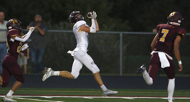 Marengo’s Gregory Backer catches a touchdown pass between Richmond-Burton’s Carsten Szumanski, left, and Joe Miller, right, during a Kishwaukee River Conference football game Friday, Sept. 9, 2022, between Richmond-Burton and Marengo at Richmond-Burton Community High School.